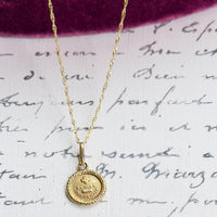 Antique gold charm necklace shown on neutral background