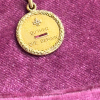 Vintage French charm inscribed with “+ qu’hier – que demain” featuring gemstone accents and engraved floral edge