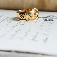 Angled view of an original 1916 English 18K gold antique buckle ring showcasing its sculptural buckle design and tapered band