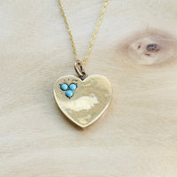 Antique English turquoise heart necklace styled on a natural wood background.