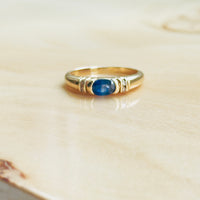Classic blue sapphire ring with diamond chip accents and ribbed gold shoulders
