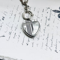 Close-up of an antique sterling silver Art Deco heart locket pendant styled on an antique watch chain.