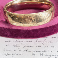 Close-up of etched floral detail on gold vintage bangle bracelet.