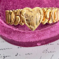 Gold bracelet with heart design on a pink velvet cushion