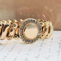Mid-century gold filled sweetheart bracelet with individually set clear paste rhinestones in milgrain collet bezels surrounding round center face