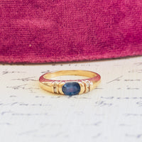 10K gold vintage ring featuring oval sapphire flanked by four diamond chips
