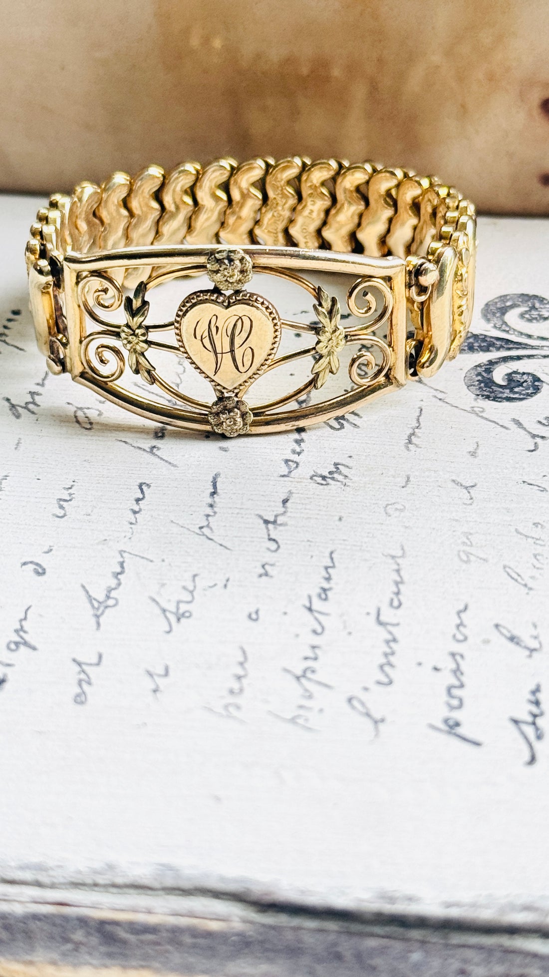 1940s gold filled sweetheart bracelet with heart monogram, displayed on antique script paper"