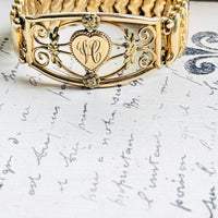 1940s gold filled sweetheart bracelet with heart monogram, displayed on antique script paper"