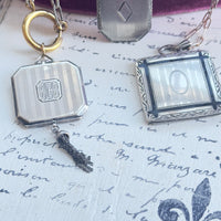Sterling silver Art Deco locket on open-link chain against handwritten script background
