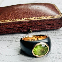 Close-up of faceted green peridot in smooth 18k bezel