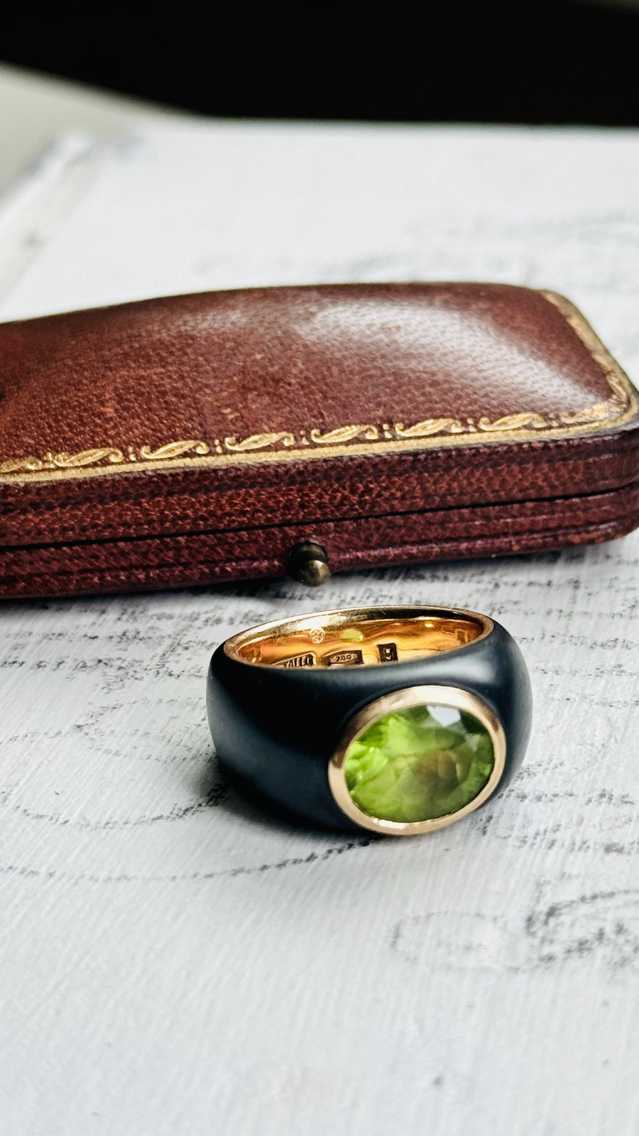 Close-up of faceted green peridot in smooth 18k bezel