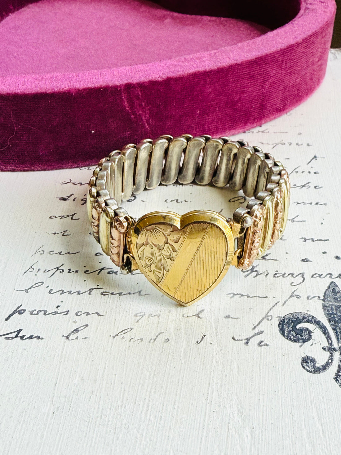 Gold heart-shaped locket on a textured surface with text