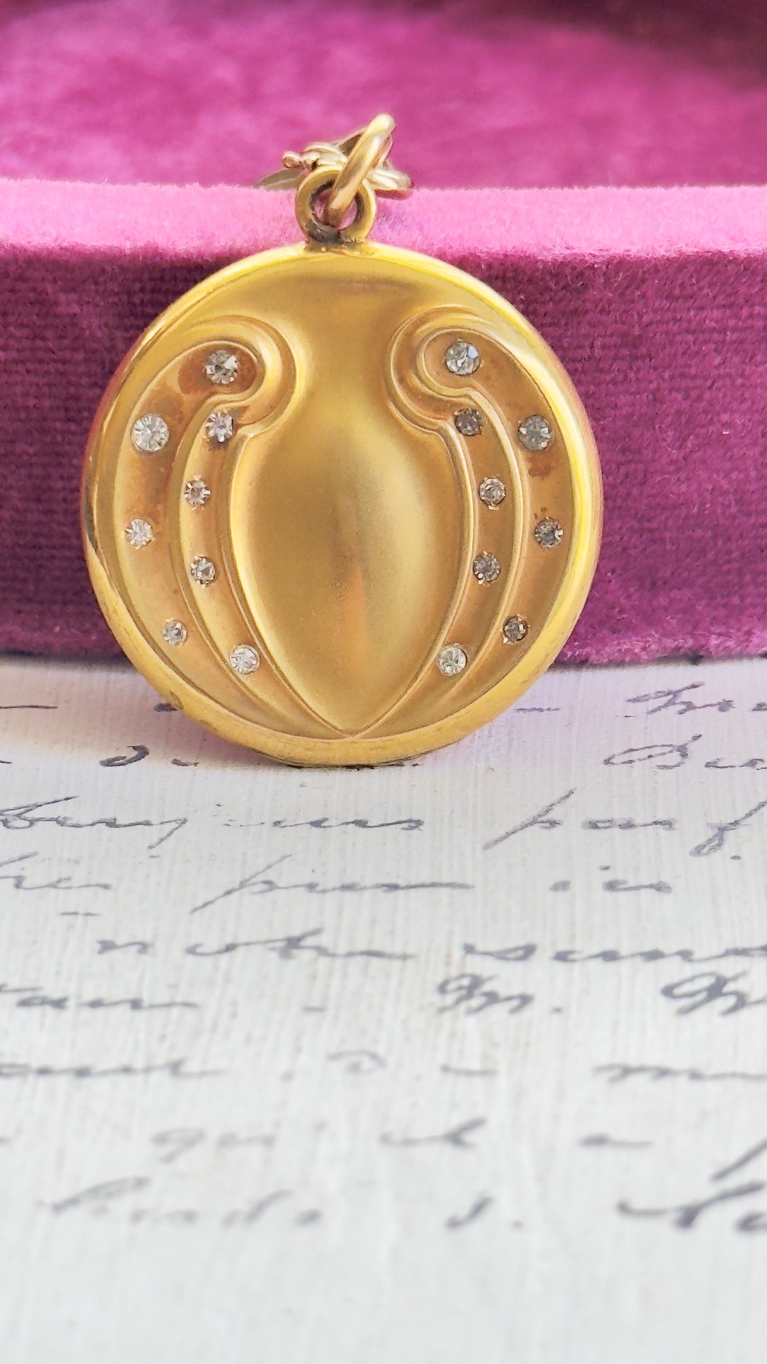 Gold-filled WH & Co. locket on long Victorian chain styled on a plum velvet jewelry box