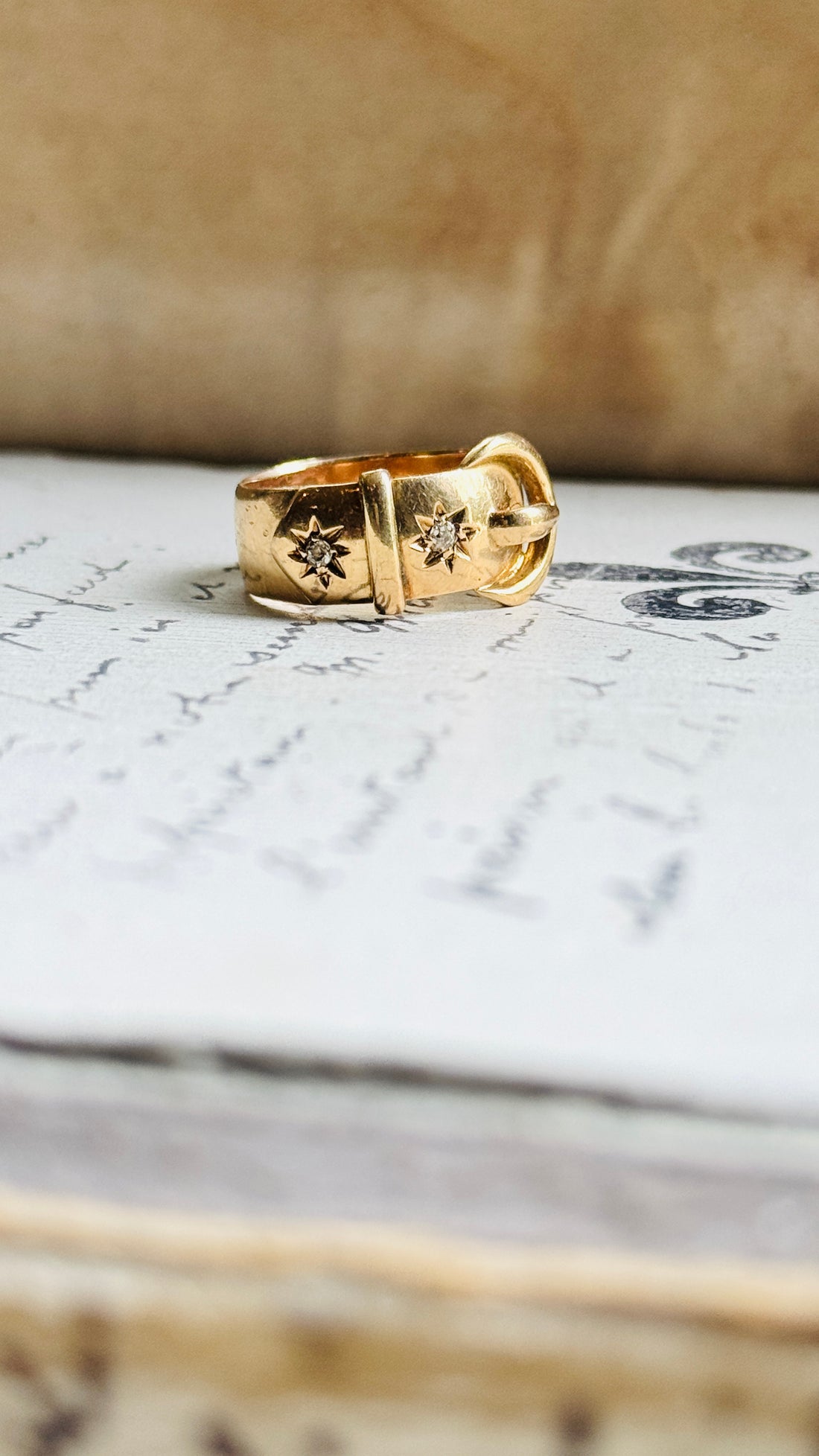 Angled view of an original 1916 English 18K gold antique buckle ring showcasing its sculptural buckle design and tapered band