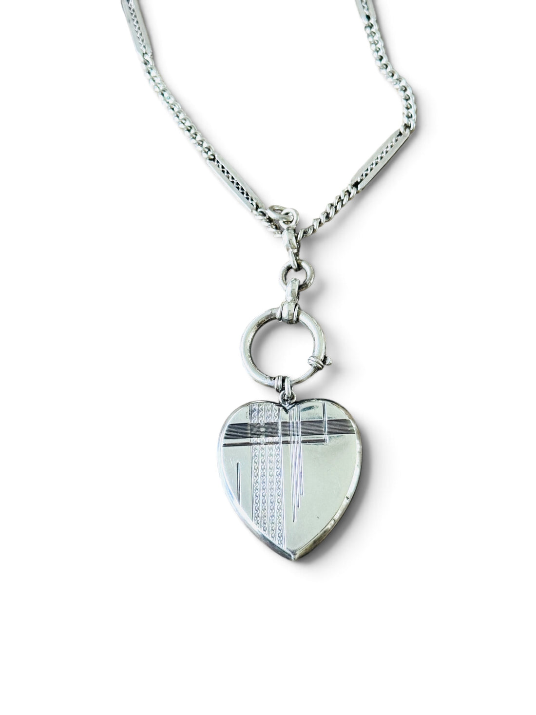 Antique Art Deco sterling silver heart locket pendant hanging from an antique silver watch chain.
