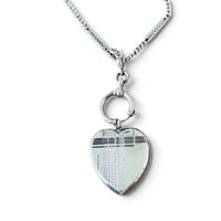 Antique Art Deco sterling silver heart locket pendant hanging from an antique silver watch chain.