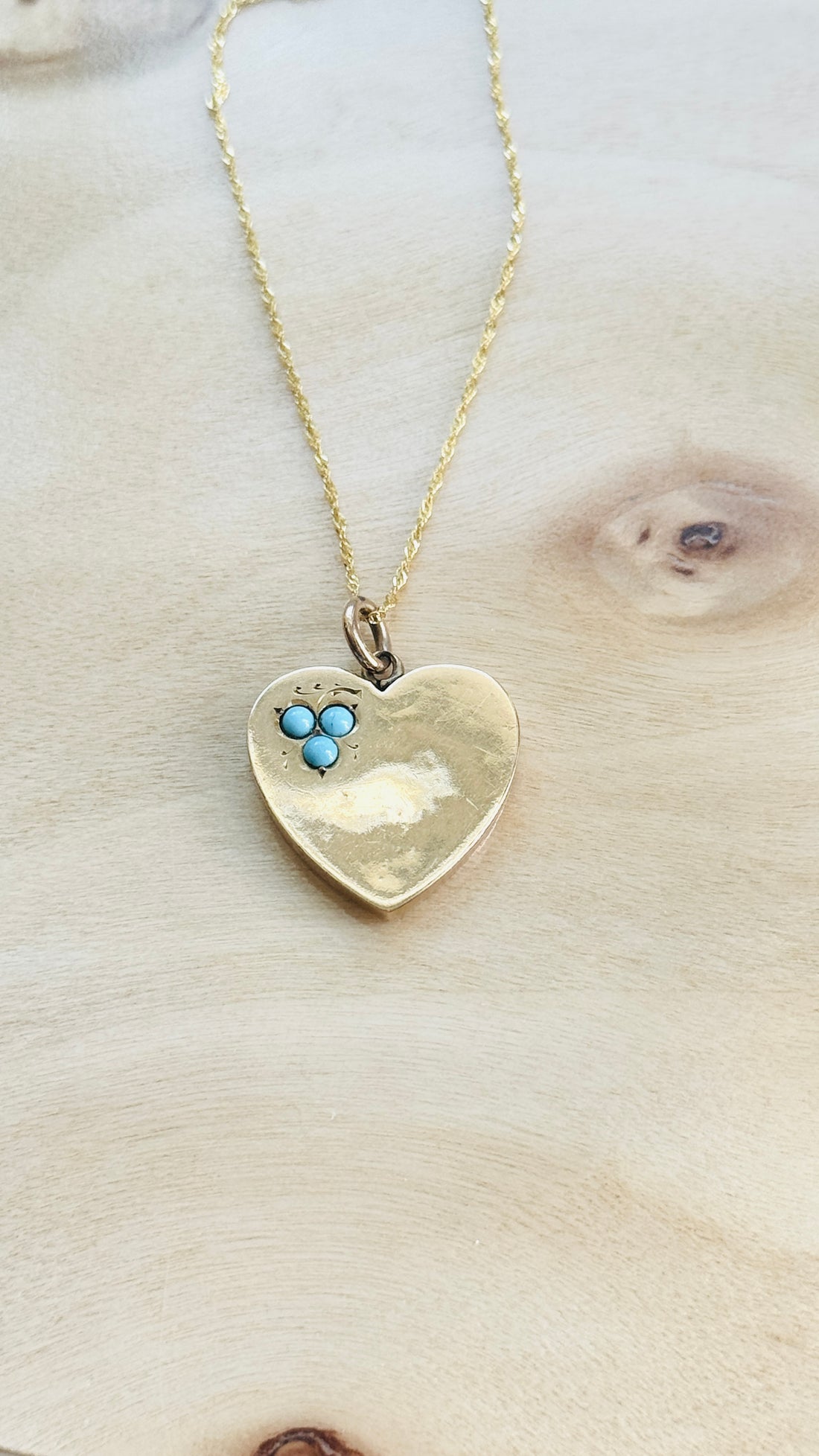 Antique English turquoise heart necklace styled on a natural wood background.