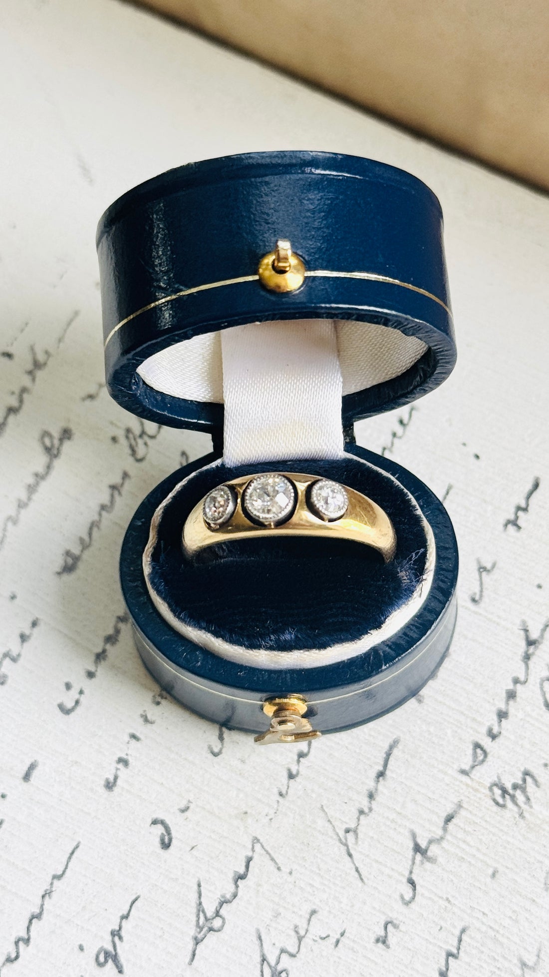 Antique diamond ring in a navy ring box, styled with vintage handwritten paper