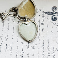 Antique sterling silver heart locket opened to reveal two compartments for photographs.