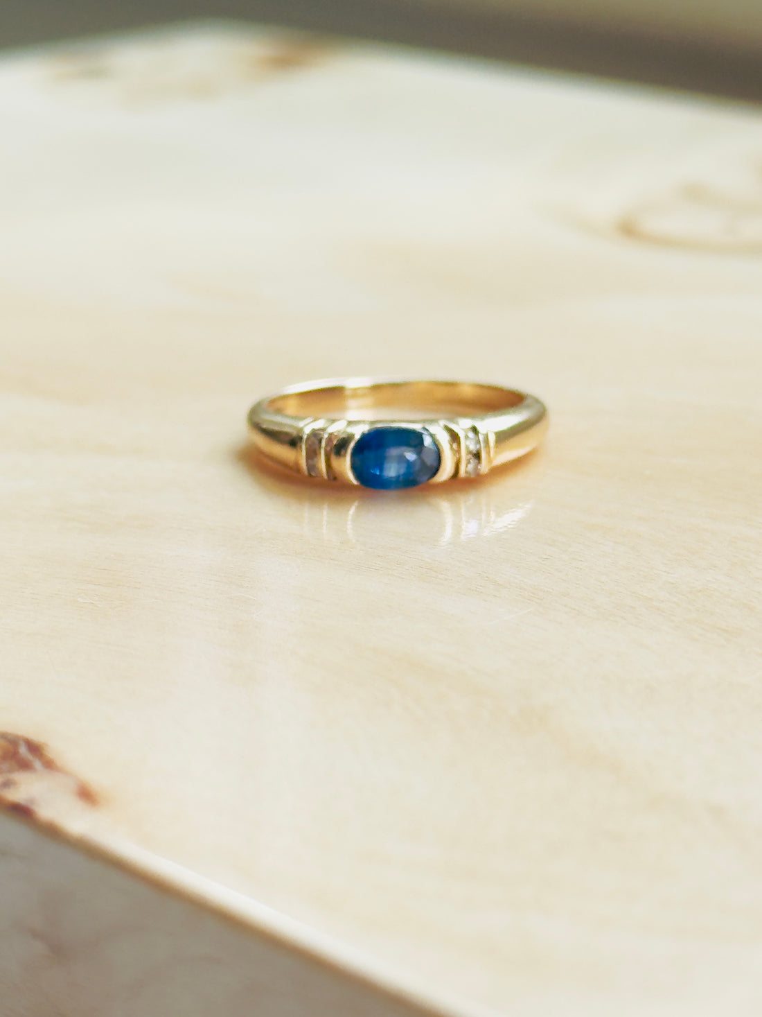 Classic blue sapphire ring with diamond chip accents and ribbed gold shoulders