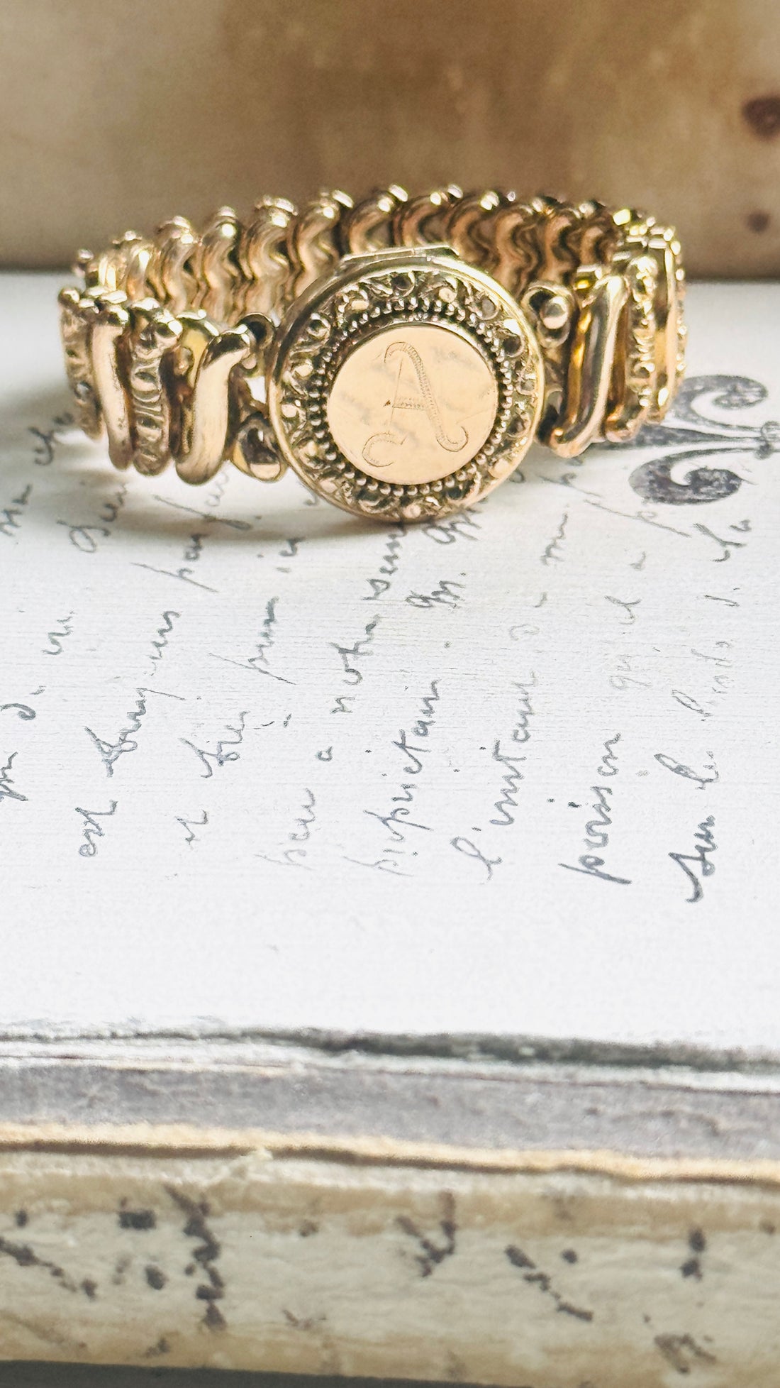 Close-up of a vintage Carmen gold-filled sweetheart expansion bracelet with engraved A monogram locket.