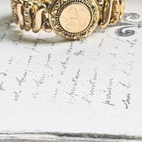 Close-up of a vintage Carmen gold-filled sweetheart expansion bracelet with engraved A monogram locket.