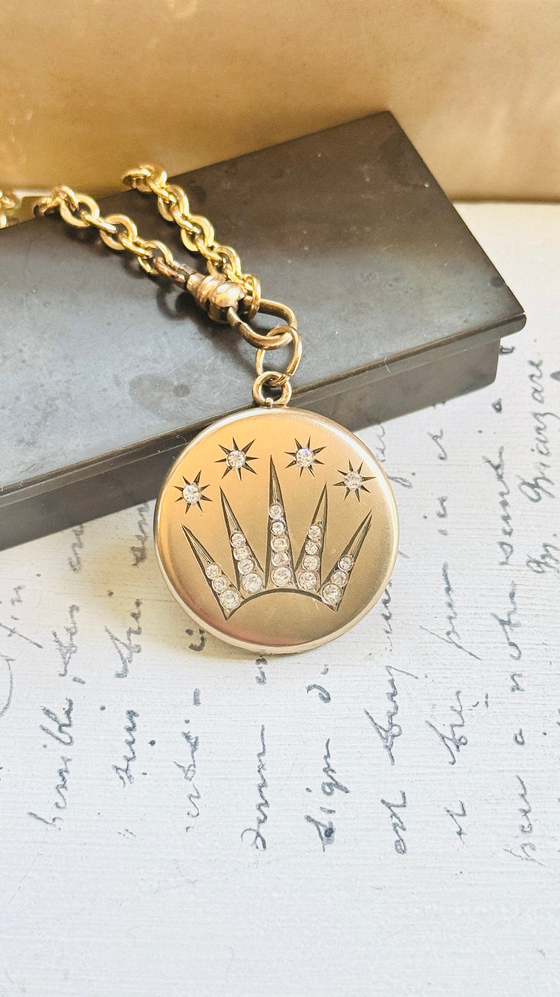 Close-up of an Edwardian gold-filled celestial locket showcasing its detailed shooting star design and original paste stone accents.