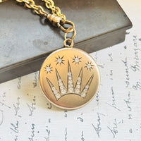 Close-up of an Edwardian gold-filled celestial locket showcasing its detailed shooting star design and original paste stone accents.