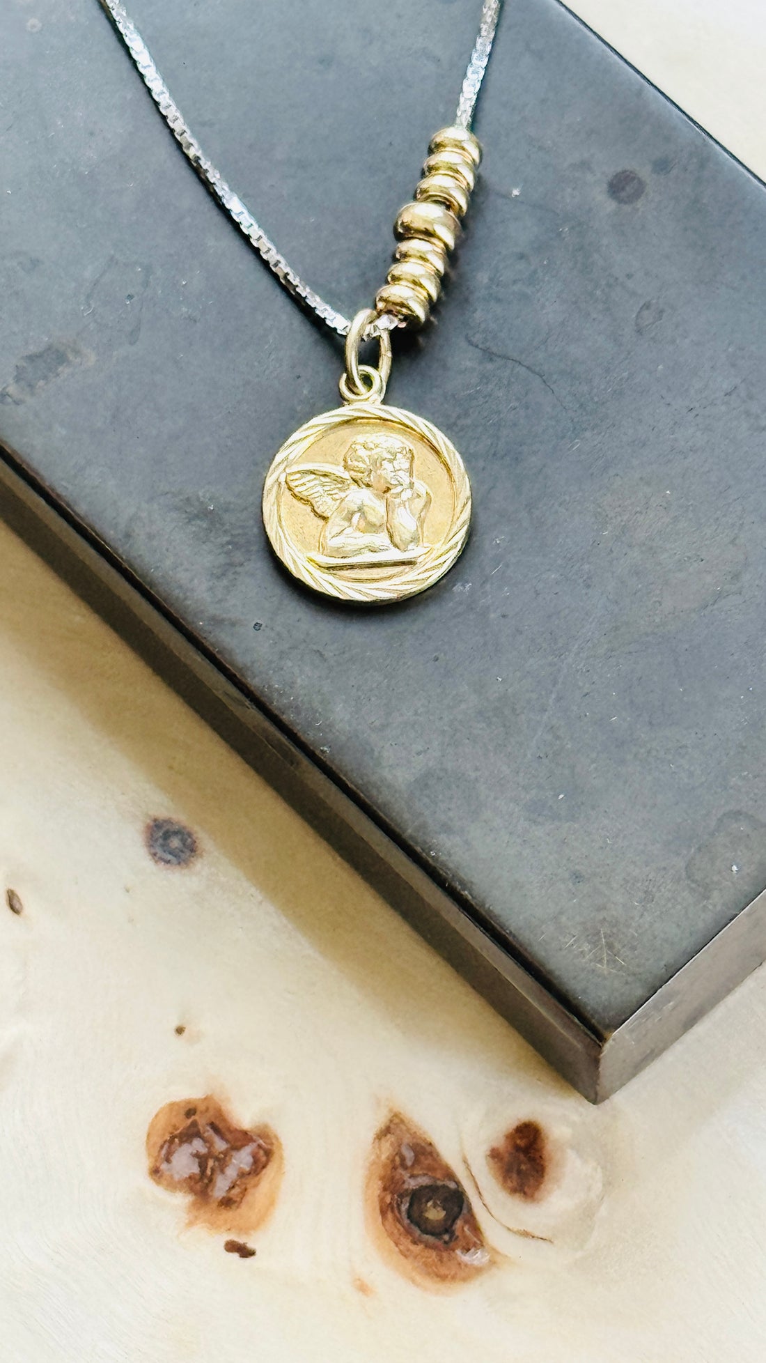Close-up of an original Victorian 14k gold cherub pendant on a sterling silver slider chain with 14k gold bead accents.