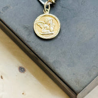 Close-up of an original Victorian 14k gold cherub pendant on a sterling silver slider chain with 14k gold bead accents.