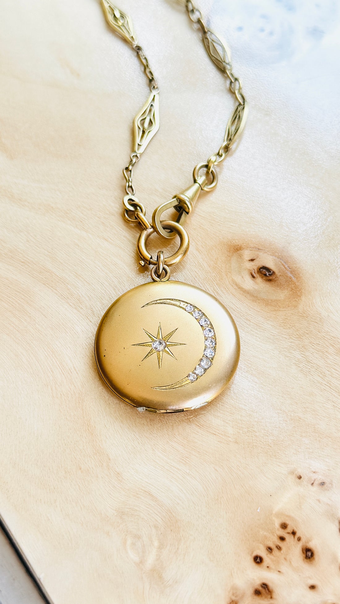 Close-up of the original Victorian celestial locket featuring a crescent moon and star with original paste stones.