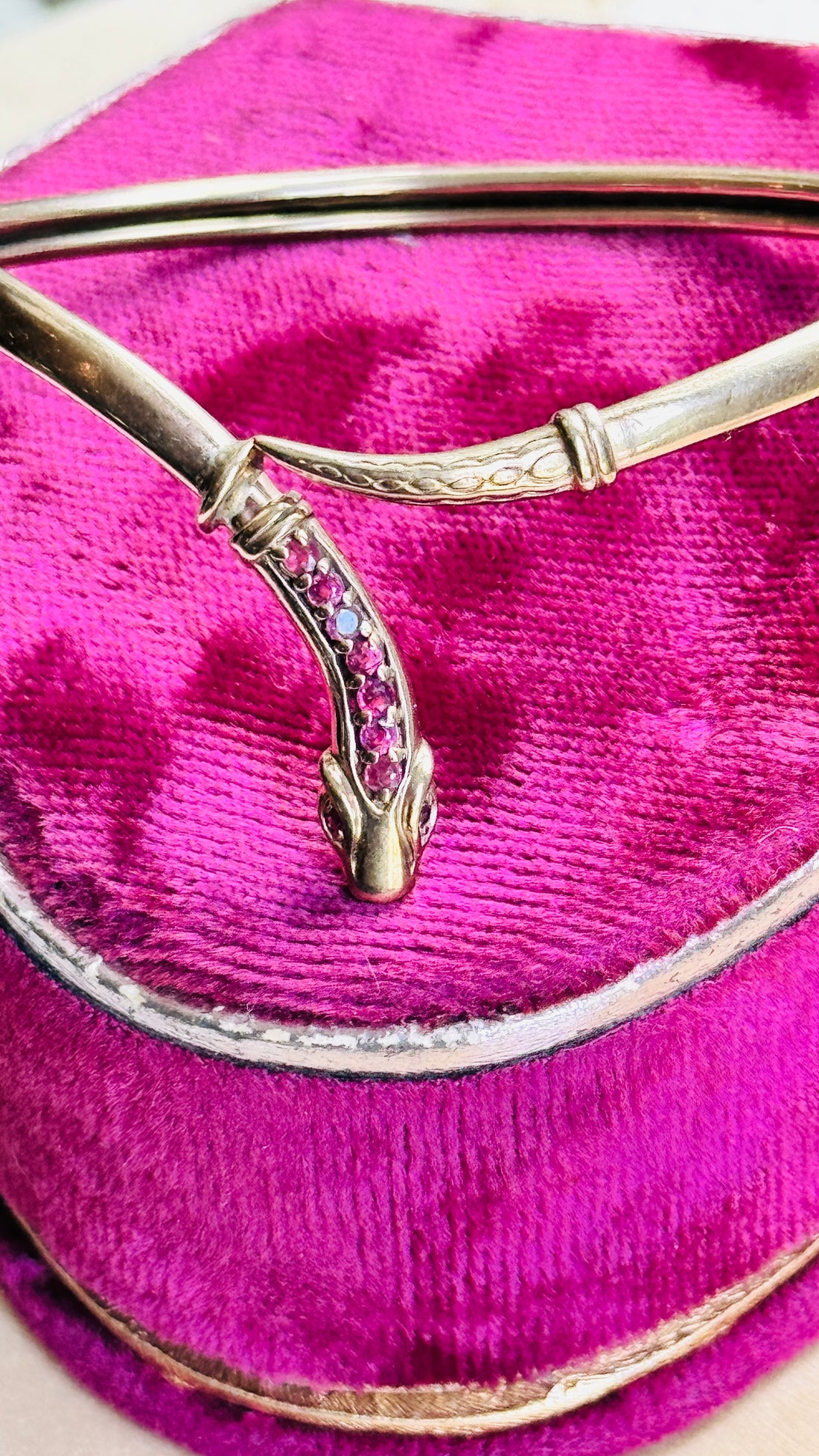 Close-up of the serpent head on a vintage gold snake bracelet showing nine natural rubies and engraved details.