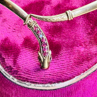 Close-up of the serpent head on a vintage gold snake bracelet showing nine natural rubies and engraved details.