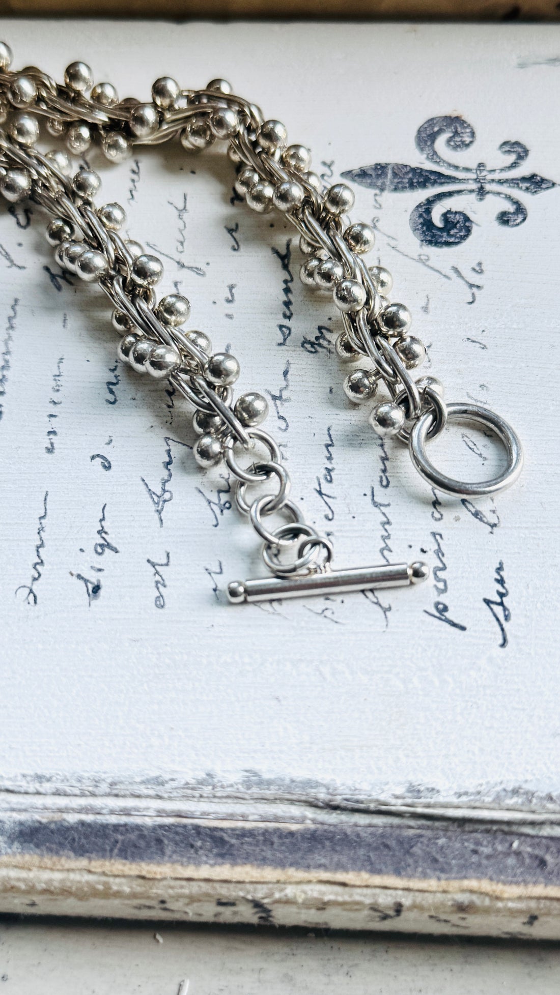 Close-up of the sterling silver toggle clasp on a vintage peppercorn necklace with 925 silver construction.
