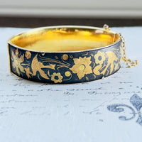 Detail of textured gold-toned decoration on dark surface of vintage hinged bangle