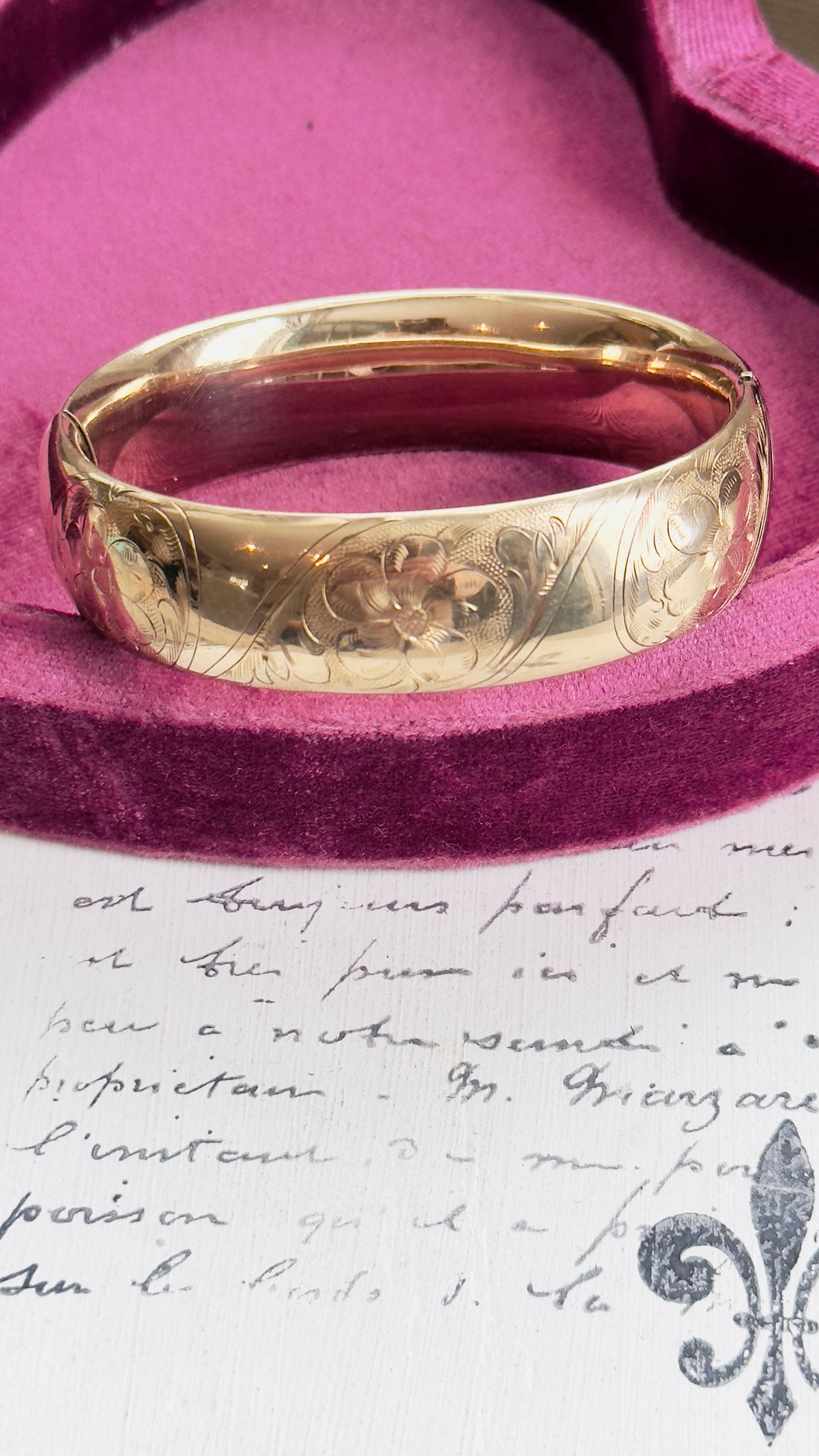 Close-up of etched floral detail on gold vintage bangle bracelet.