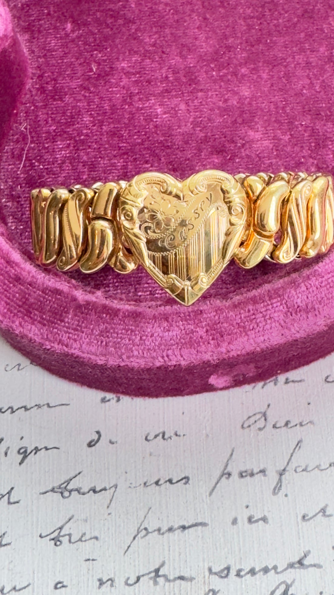 Gold bracelet with heart design on a pink velvet cushion