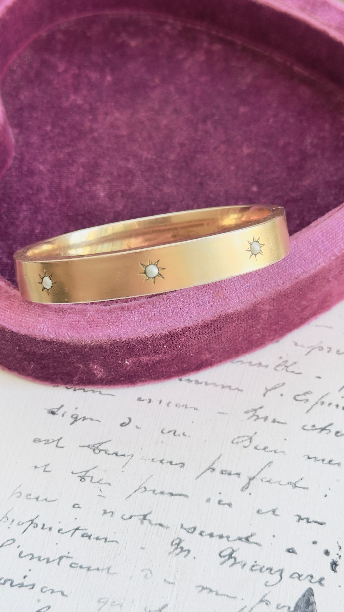 Gold filled bangle bracelet showing three starbursts with seed pearls