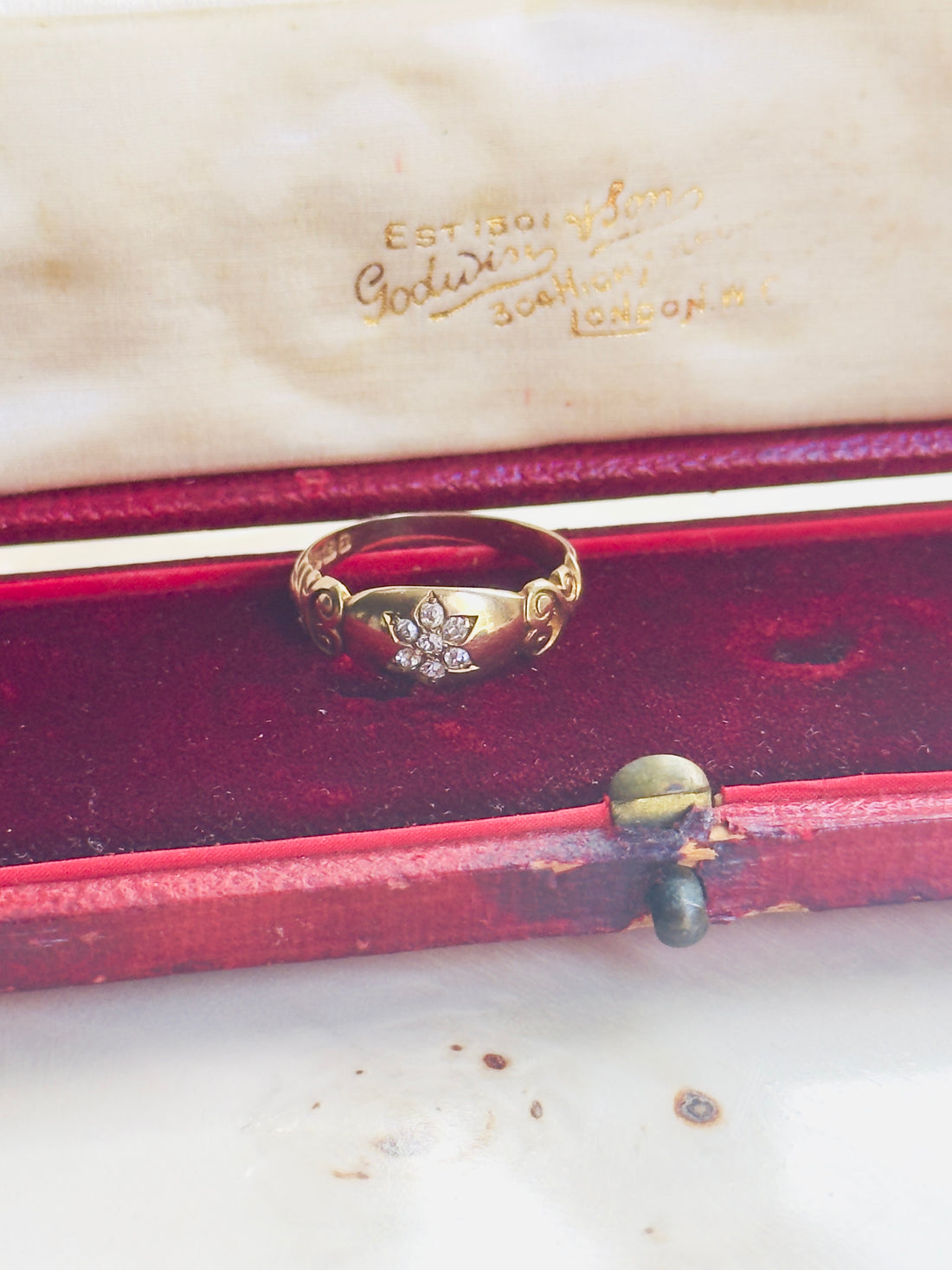 Gold ring with diamonds in a red jewelry box on a white surface
