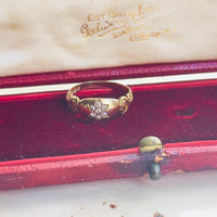 Gold ring with diamonds in a red jewelry box on a white surface