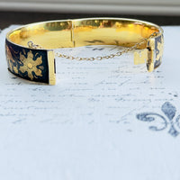 Open view of vintage black and gold bangle showing box clasp and safety chain