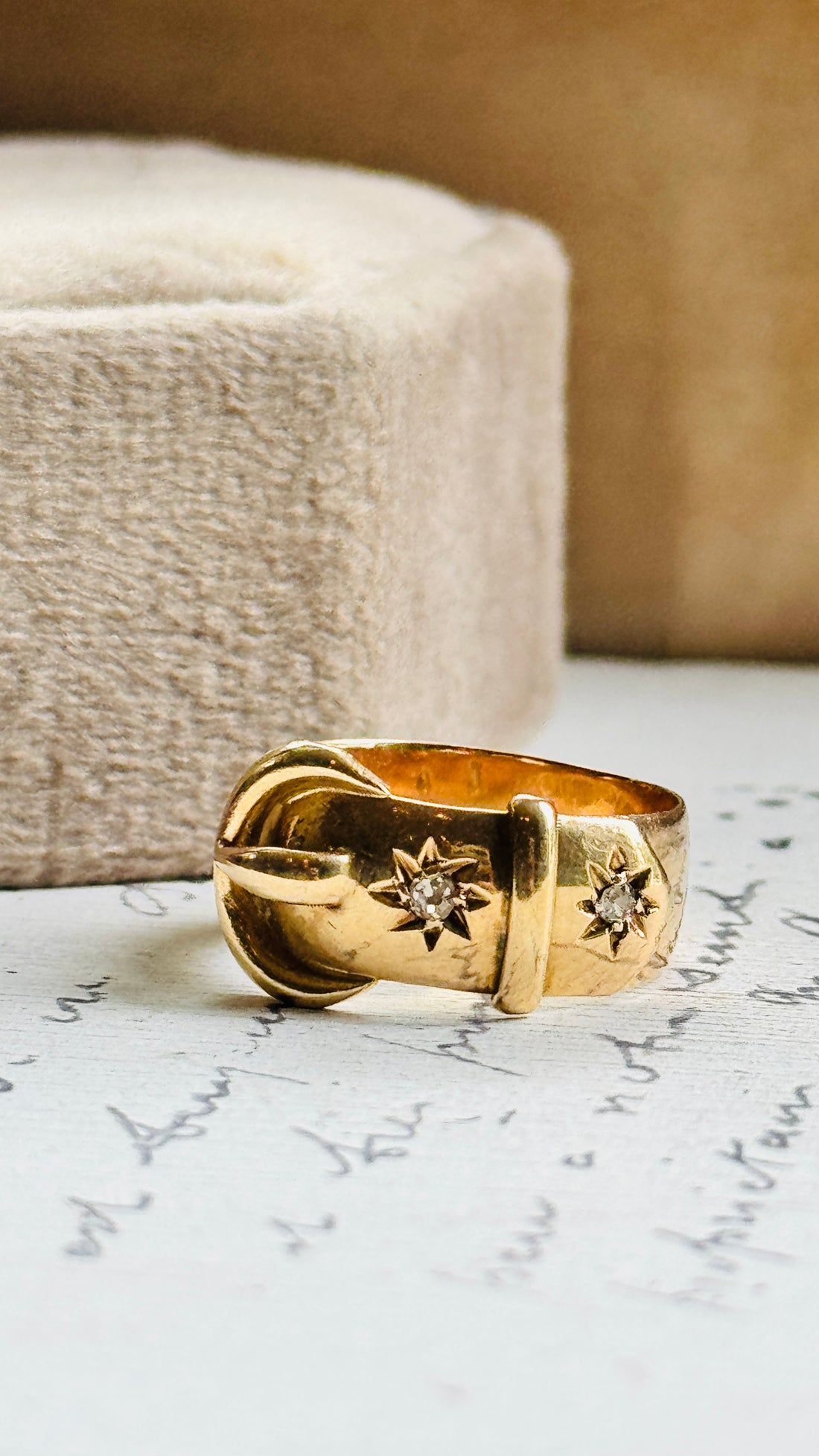 Original 1916 English 18K gold buckle ring with old European cut diamonds styled on antique paper, highlighting its sculptural buckle motif.