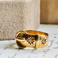 Original 1916 English 18K gold buckle ring with old European cut diamonds styled on antique paper, highlighting its sculptural buckle motif.