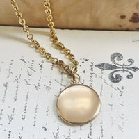 Reverse of an antique Edwardian gold-filled locket suspended from its original antique watch chain.