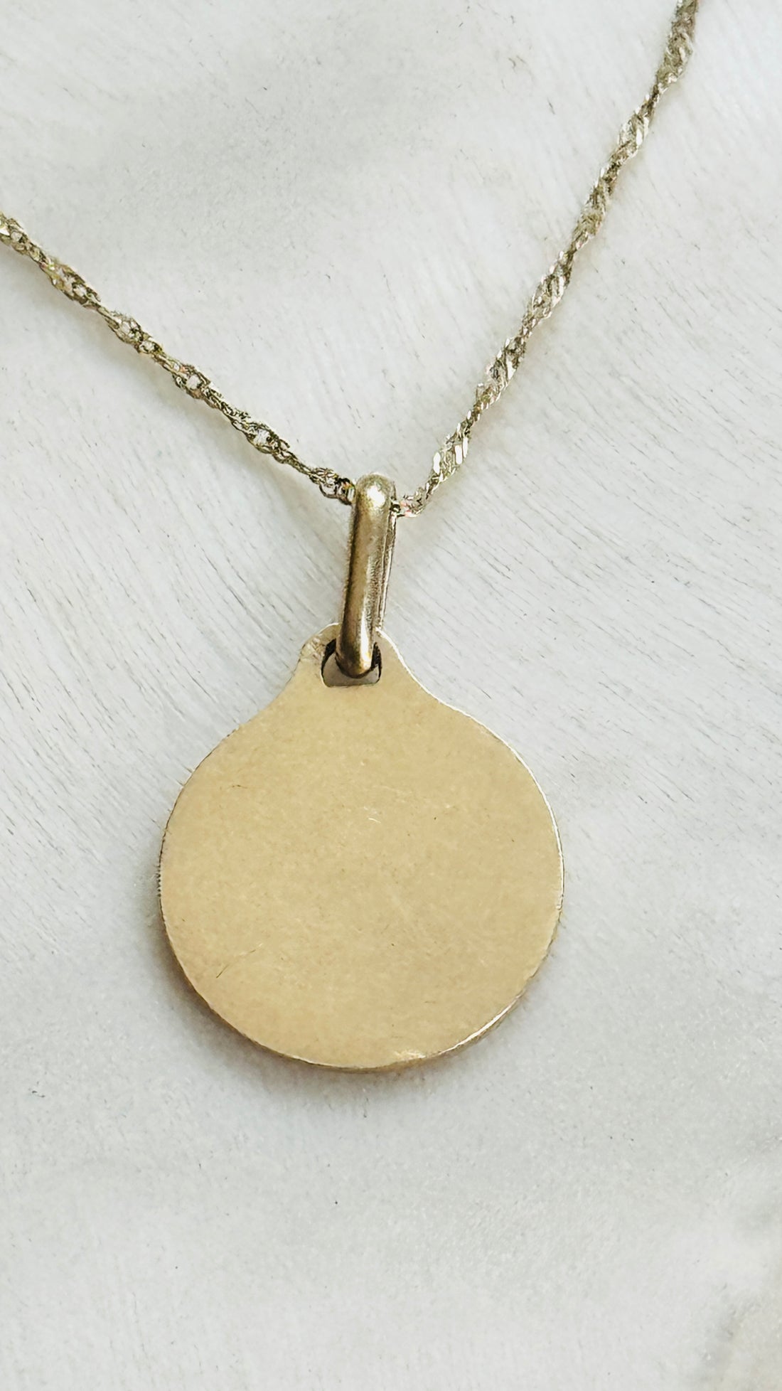 Reverse of an original 18k gold Alphonse Augis French Love Token pendant showing the polished back.