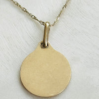 Reverse of an original 18k gold Alphonse Augis French Love Token pendant showing the polished back.