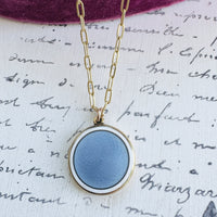 Round enamel locket with blue center and white border, gold frame