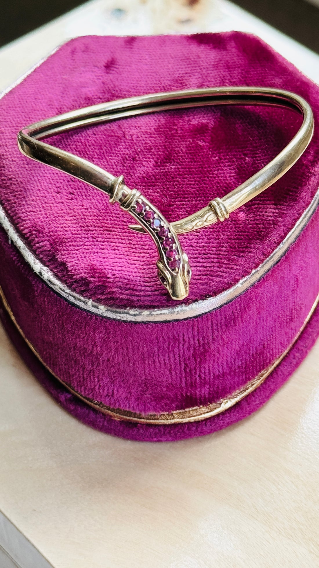 Top view of a vintage gold snake bracelet featuring a tapered engraved tail and ruby-set serpent head.