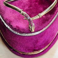 Top view of a vintage gold snake bracelet featuring a tapered engraved tail and ruby-set serpent head.