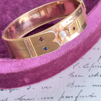 Victorian 14k gold hinged bangle with pearl center and red and blue starburst accents
